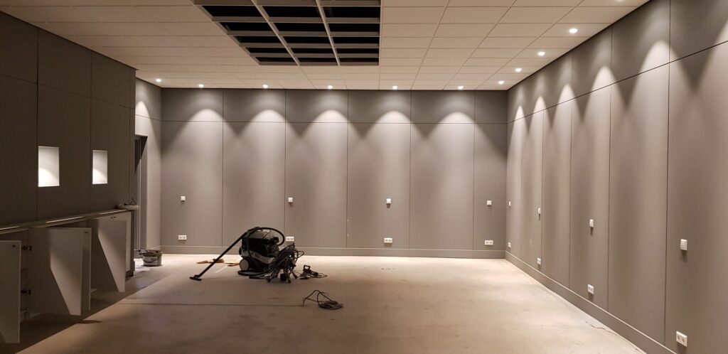 Large room during renovation with grey panelled walls and recessed ceiling lighting